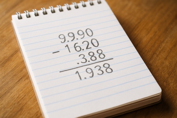 A notepad with handwritten decimals being subtracted for a grocery bill