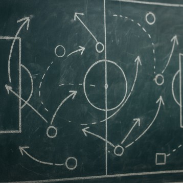 A chalkboard filled with tactical sports diagrams to illustrate real-time adaptation